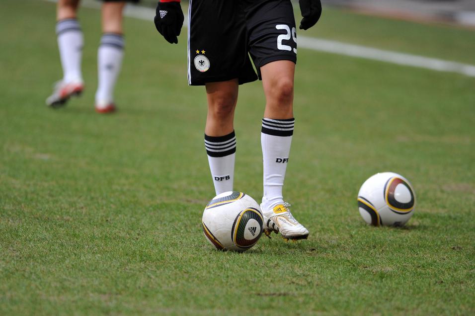 Nahaufnahme eines Fußballspielers mit einem Ball auf dem Rasen, im Hintergrund ein weiterer Ball.